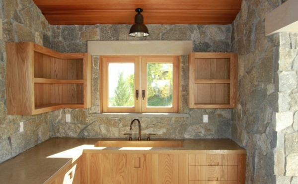 каменна стена вътре в красива малка кухня с дървени рафтове