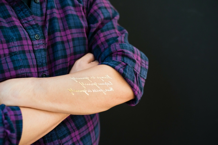 lijepe tetovaže zlatne riječi stoje na ruku i uljepšaju tijelo ljubičasto plavu košulju