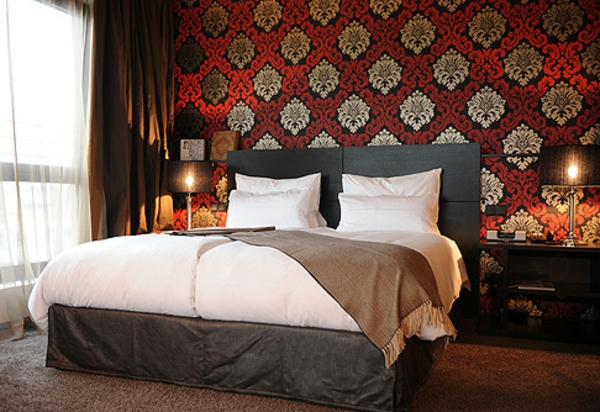 fundas de edredón blanco y papel tapiz con plantillas rojas y doradas en el dormitorio