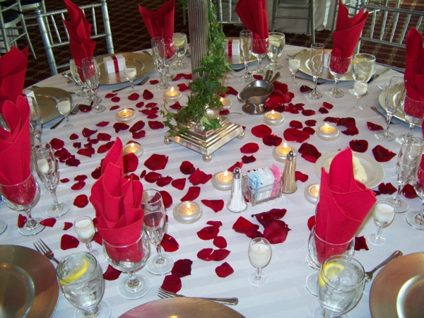 червени салфетки в стъкловиден бял таван и червени розови листенца - идеи за парти декорация