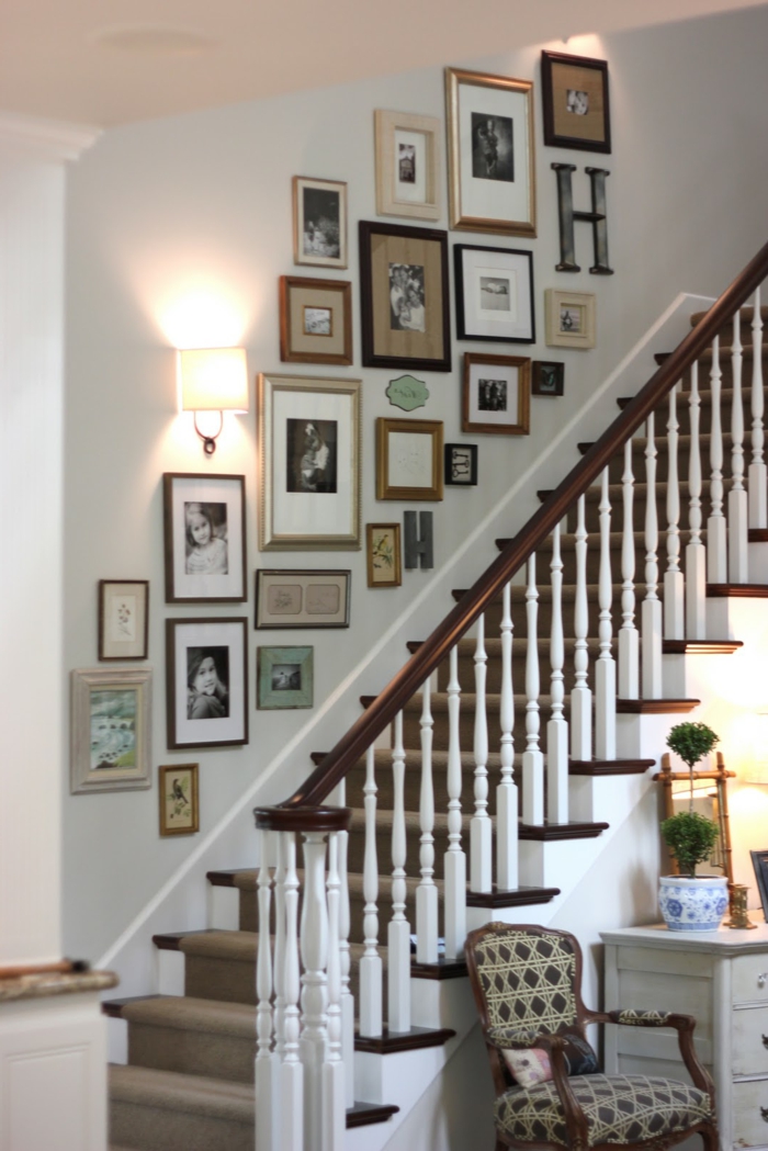 Zidna stubišta s mnogo fotografija i svjetiljka, fotelja s geometrijskim uzorkom
