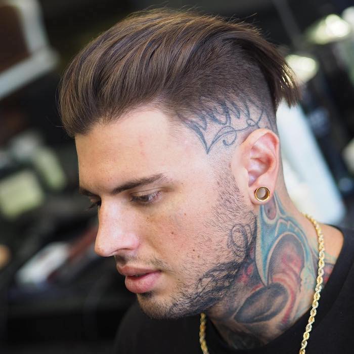 Izbojnik muškarca na tetovaži na glavi pod frizure koja odgovara stilu tetovaža
