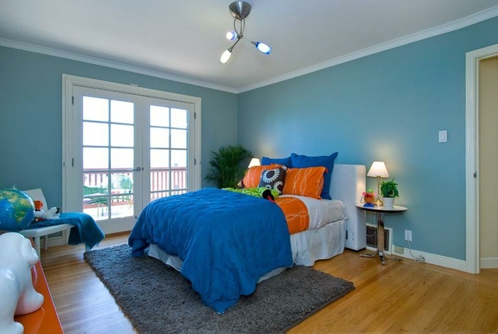 स्टड दीवारों और नीले रंग की दीवार में आरामदायक बेडरूम
