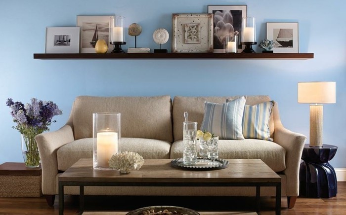 χρώμα του τοίχου μπλε ταπετσαρία καναπέ κρέμα-ξύλο τραπέζι-κεριά-νύχτα λάμπα στρογγυλής τραπέζης-λουλούδι-βάζο-βασιλική-ριγέ μαξιλάρια