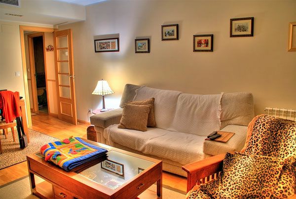 Salon design avec une table gigogne en bois, un fauteuil léopard, des photos sur le mur