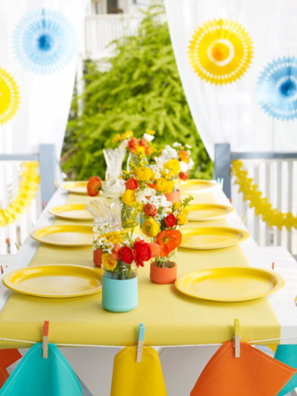 kaunis kesäpöydän koristelu monien värikkäiden kukkien ja keltaisten levyjen kanssa