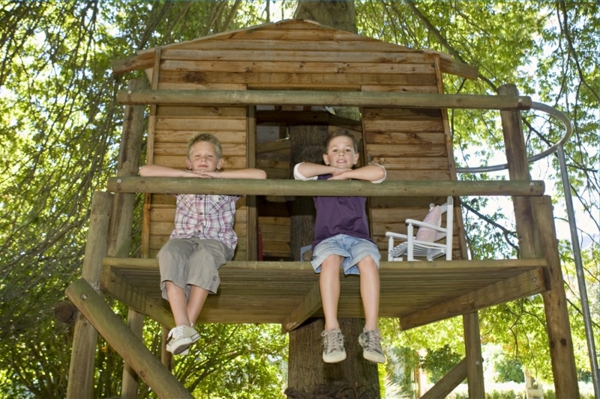 Cabane dans les arbres de deux enfants assis sur le balcon